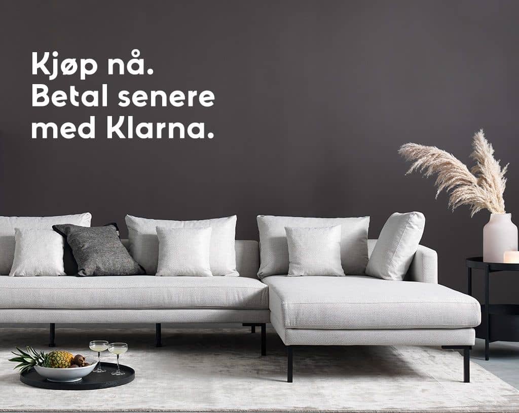 Lys grå hjørnesofa med puter i en stue, med tekst om å kjøpe nå og betale senere med Klarna.